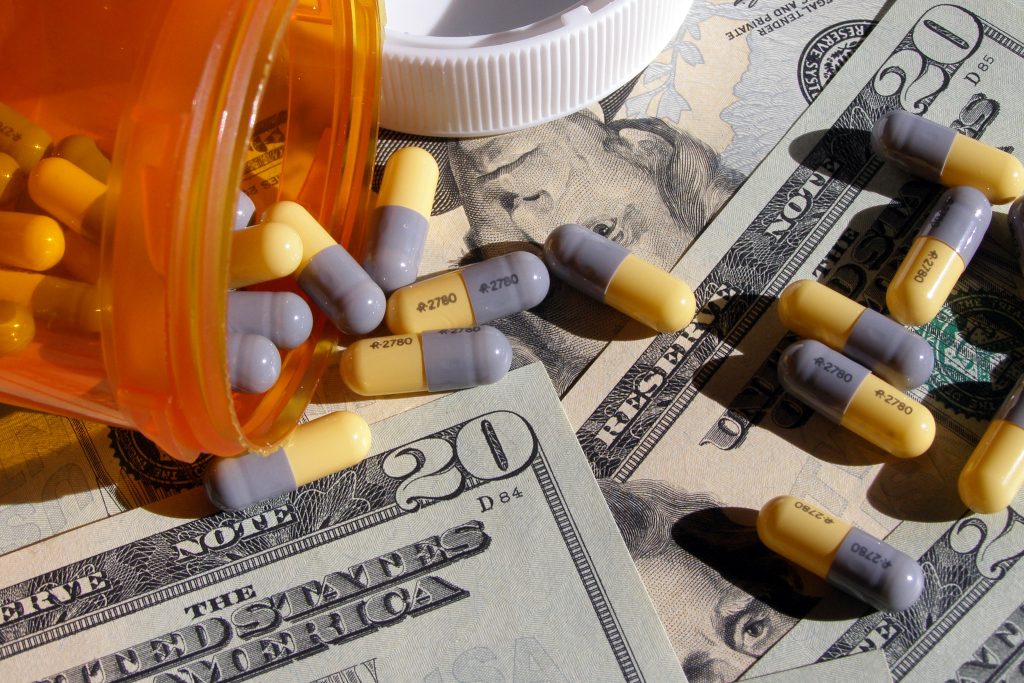 Photo showing a closeup of prescription pills strewn out across twenty dollar bills